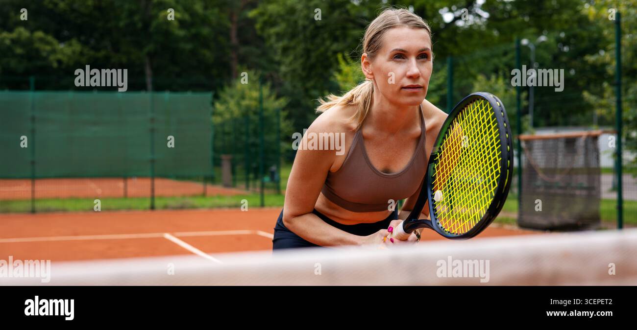 tennista donna concentrata su un campo di terra battuta all'aperto, in bilico. banner con spazio di copia Foto Stock