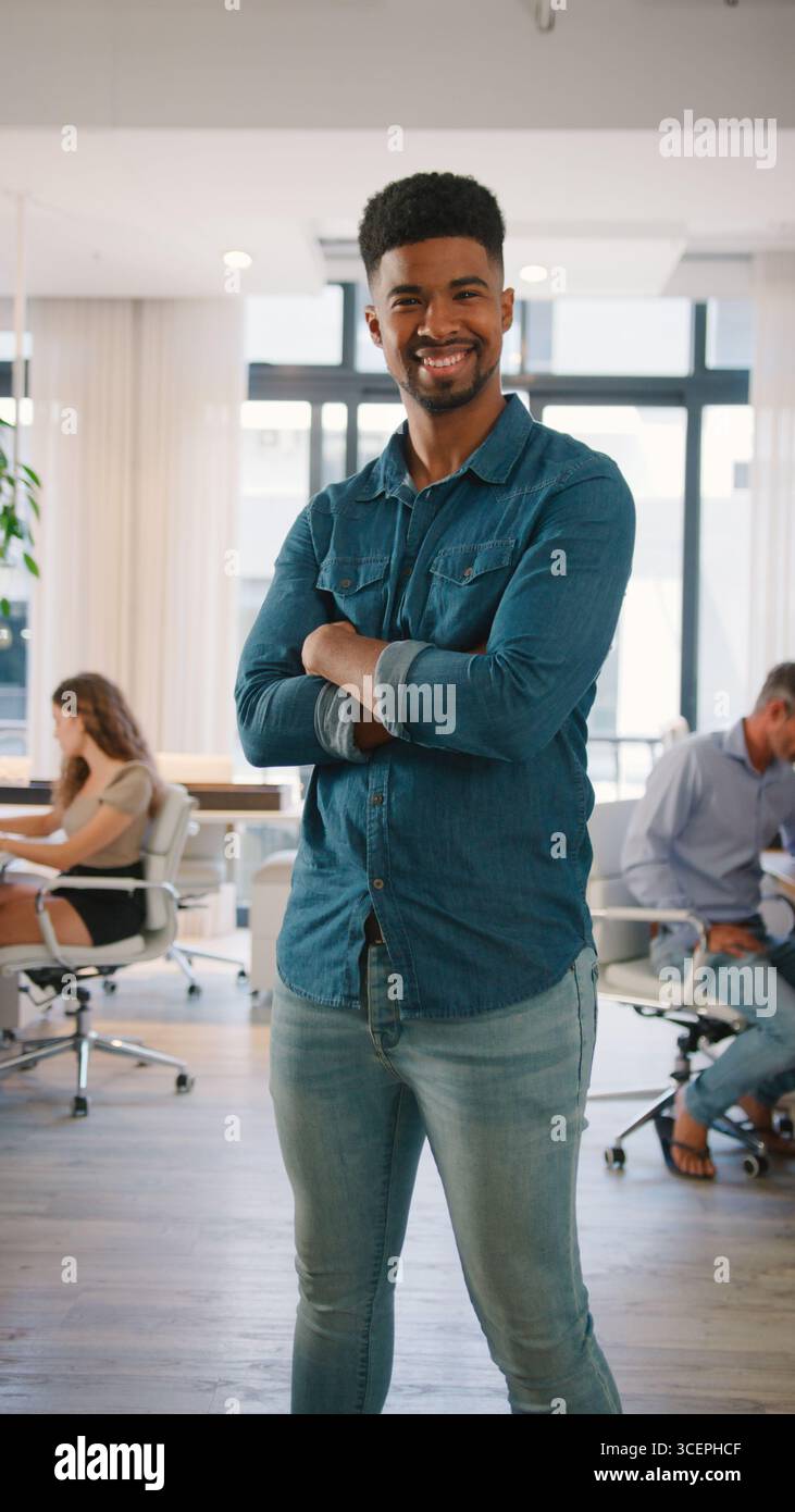 Ritratto di giovane uomo d'affari sorridente in piedi in Modern Office Foto Stock