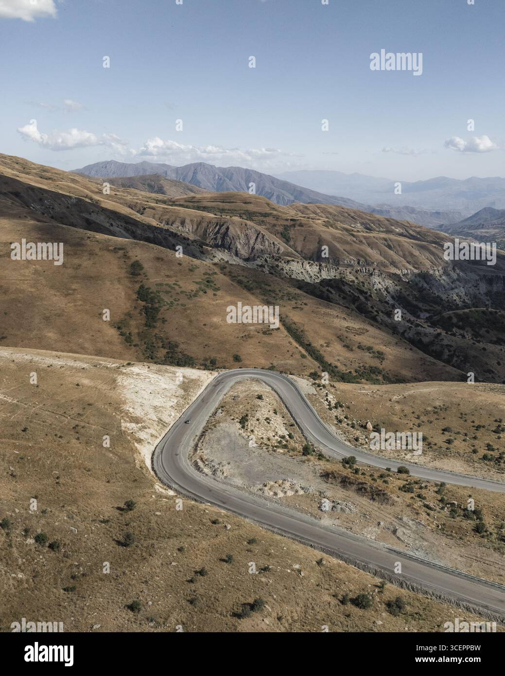 Vista aerea di una strada tortuosa che attraversa il paesaggio arido, le montagne lontane che svaniscono all'orizzonte, il passo dei Vardenyats, Vayots Dzor, Armenia. Foto Stock