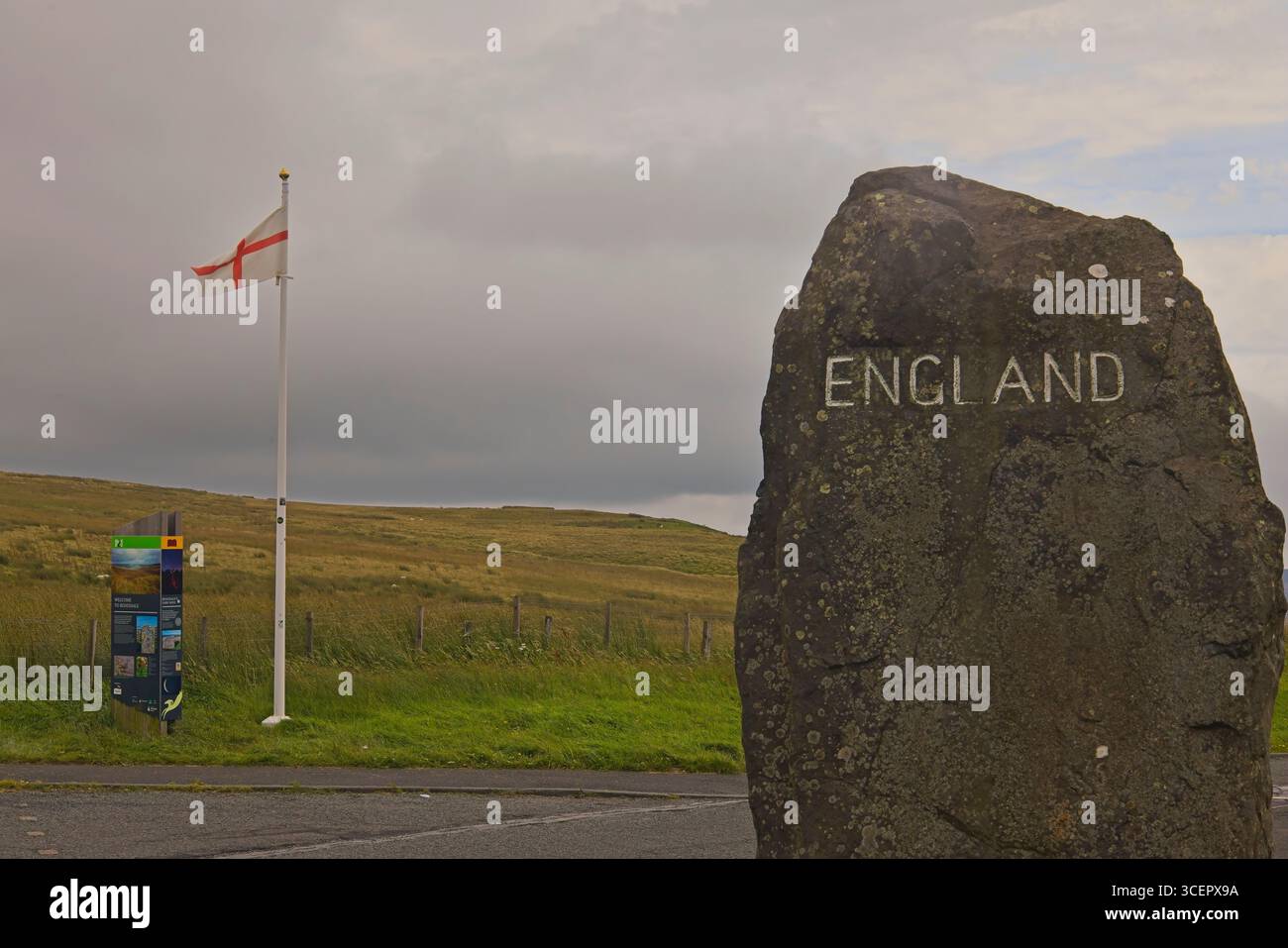 Il confine con l'Inghilterra a Carter Bar sul confine anglo-scozzese, Northumberland, Inghilterra, con la bandiera di San Giorgio che sventola accanto al cartello in pietra inciso. Foto Stock
