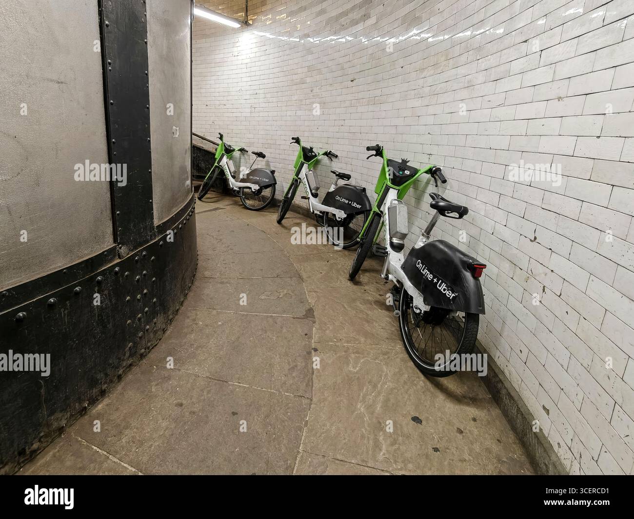 Londra, Regno Unito. 19 agosto 2025. I cicli di noleggio delle calce abbandonati sono stati scaricati ai piedi delle scale del tunnel pedonale di Greenwich, sotto il Tamigi, tra Cutty Sark a sud e Island Gardens a nord, presumibilmente perché i cavalieri li trovavano troppo pesanti per salire le scale fino in superficie. Anche se all'esterno e all'interno del tunnel ci sono molti segnali che dicono "No Cycling", ci sono quelli che ignorano la sicurezza dei pedoni. Crediti: Stephen Chung / Alamy Live News Foto Stock