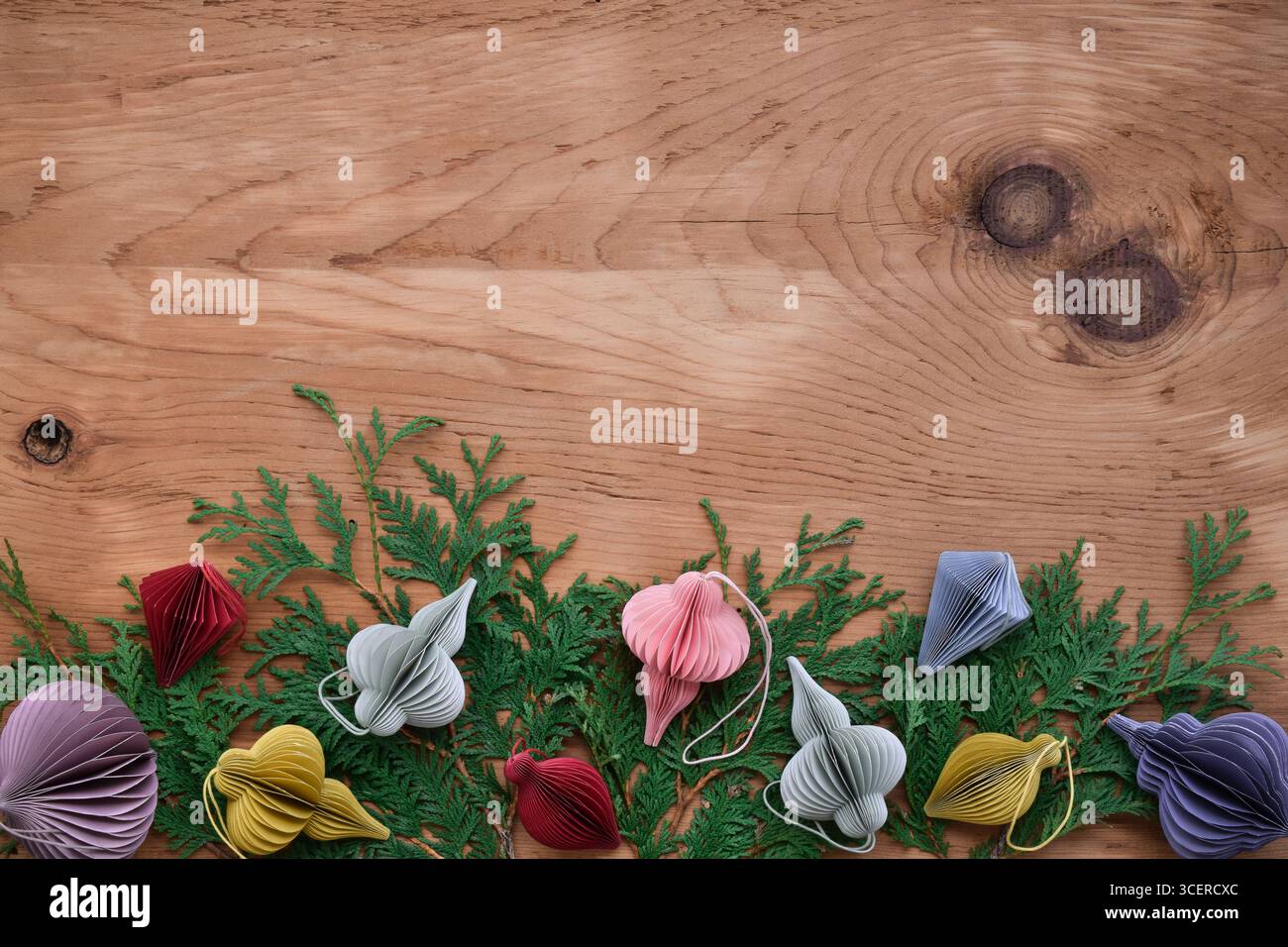 Fondo in legno con ornamenti natalizi di carta nordica con rami sempreverdi Foto Stock