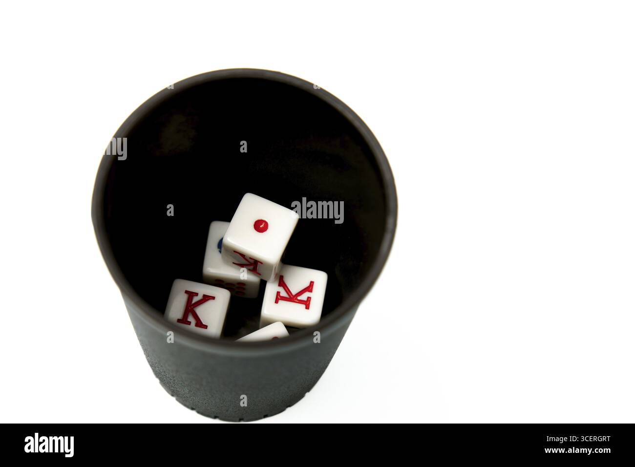Quattro dadi bianchi che mostrano il re e uno che riposa in una tazza nera di dadi su uno sfondo bianco, suggerendo il gioco d'azzardo e i giochi d'azzardo Foto Stock