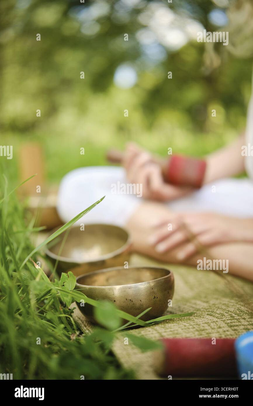 I partecipanti sono impegnati in una tranquilla sessione di meditazione all'aperto, suonando abilmente ciotole cantanti Foto Stock