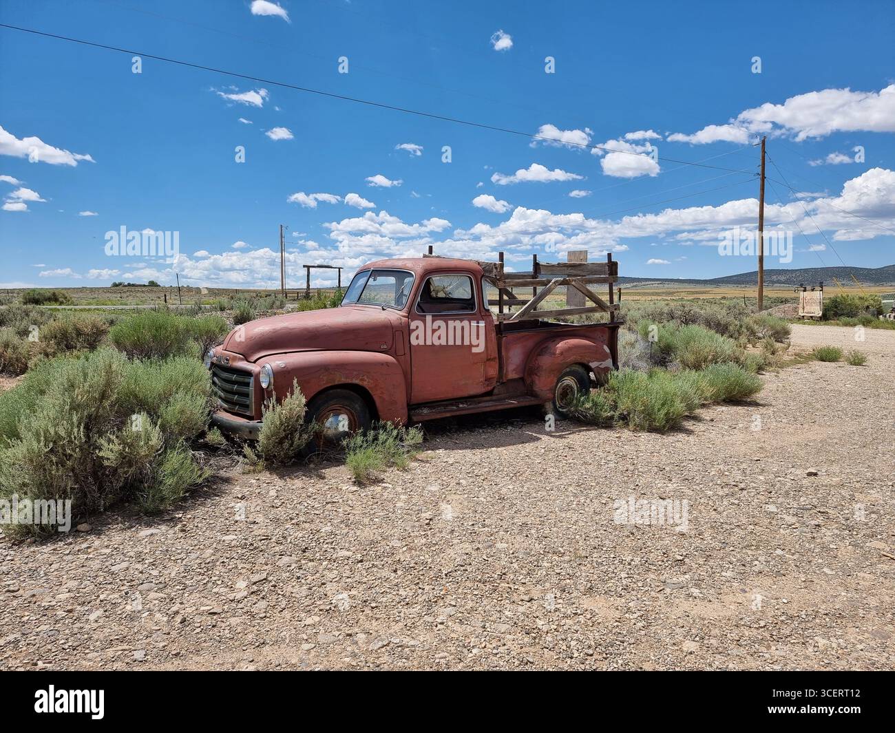 Vecchia auto d'epoca arrugginita lungo una strada sterrata nella prateria del New Mexico; pick-up rosso GMC; camion arrugginito; camion rosso GMC; camion retro GMC - Immagine stock catturata con smartphone