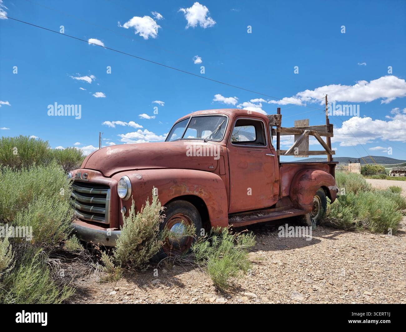 Vecchia auto d'epoca arrugginita lungo una strada sterrata nella prateria del New Mexico; pick-up rosso GMC; camion arrugginito; camion rosso GMC; camion retro GMC Foto Stock