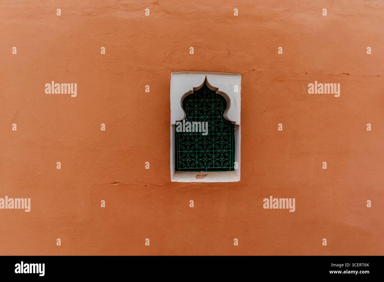 Una finestra decorativa con intricati tralicci adagiati su una calda parete arancione, che mostra la bellezza architettonica tradizionale e l'eleganza culturale. Foto Stock