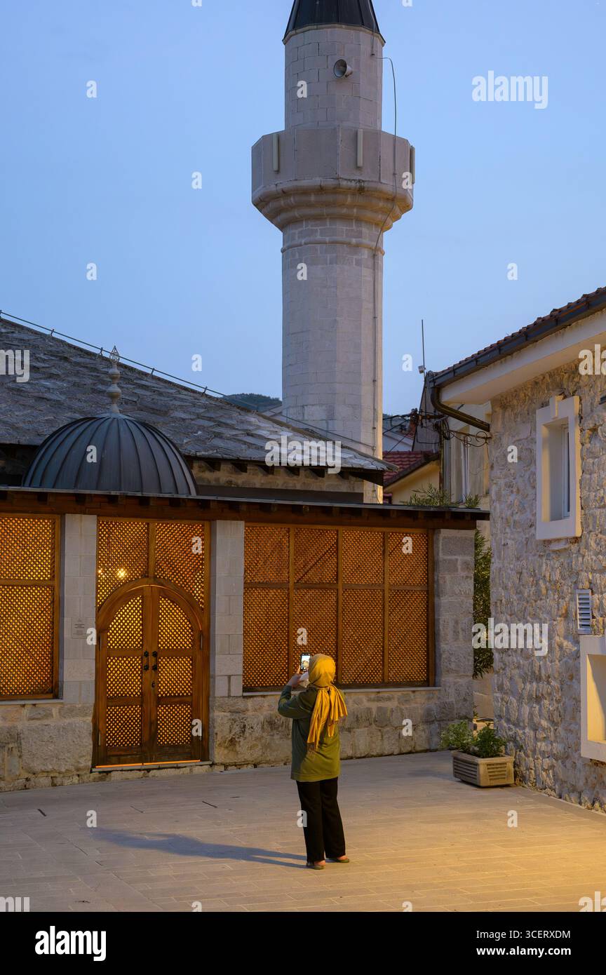 Una persona cattura la bellezza della moschea di Osman Pasina mentre la luce della sera tramonta a Trebinje. Foto Stock