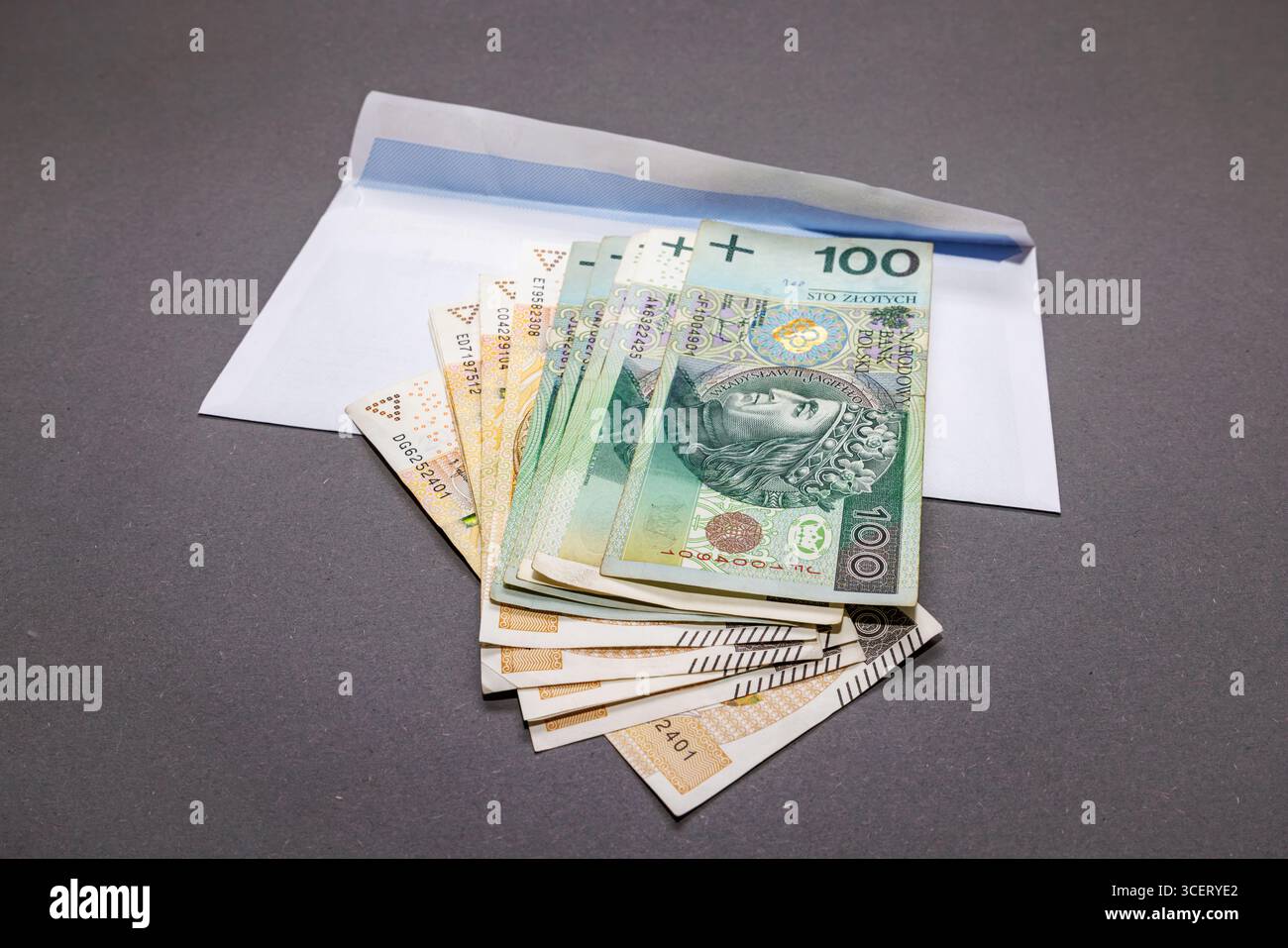 Banconote di valuta polacca in tagli da centoduecento zloty con una busta bianca su sfondo grigio. Primo piano zloty polacco. Foto Stock