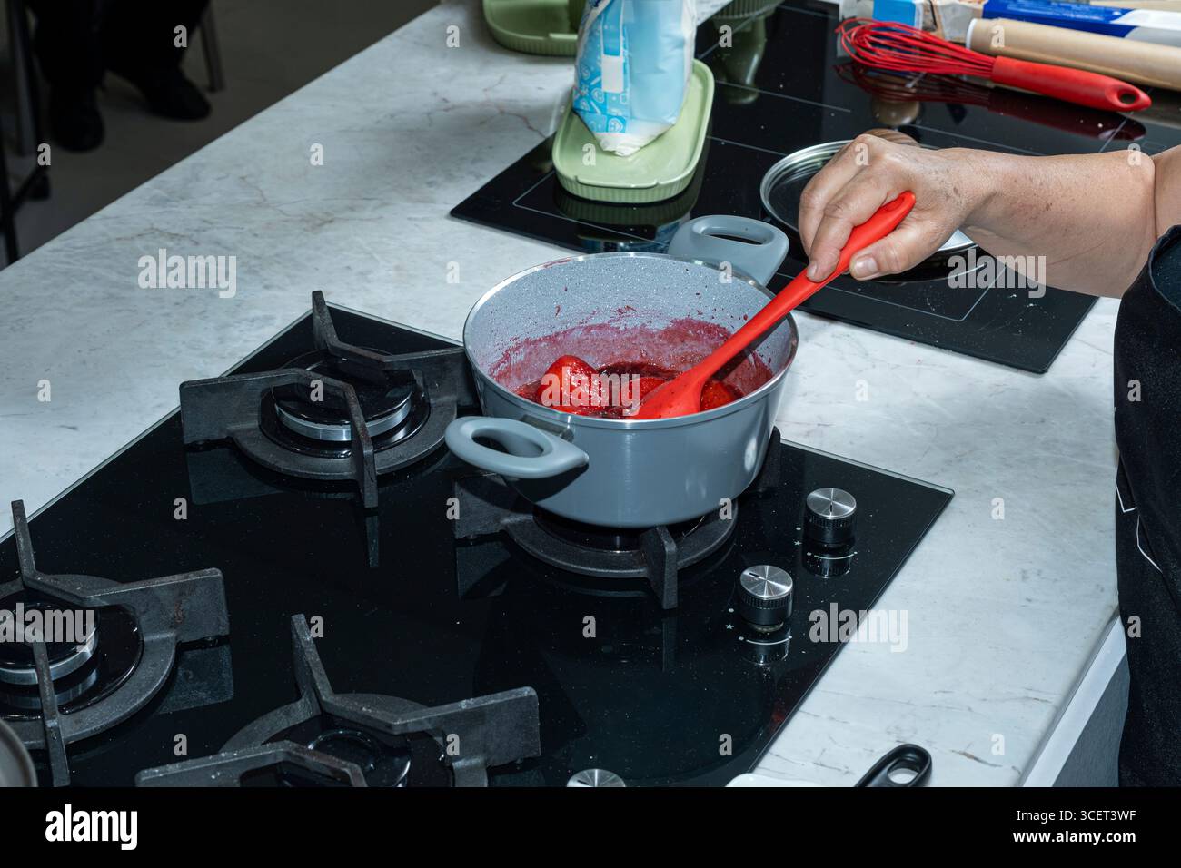 L'assistente dello chef prepara il condimento con i frutti di bosco per la torta. Foto Stock