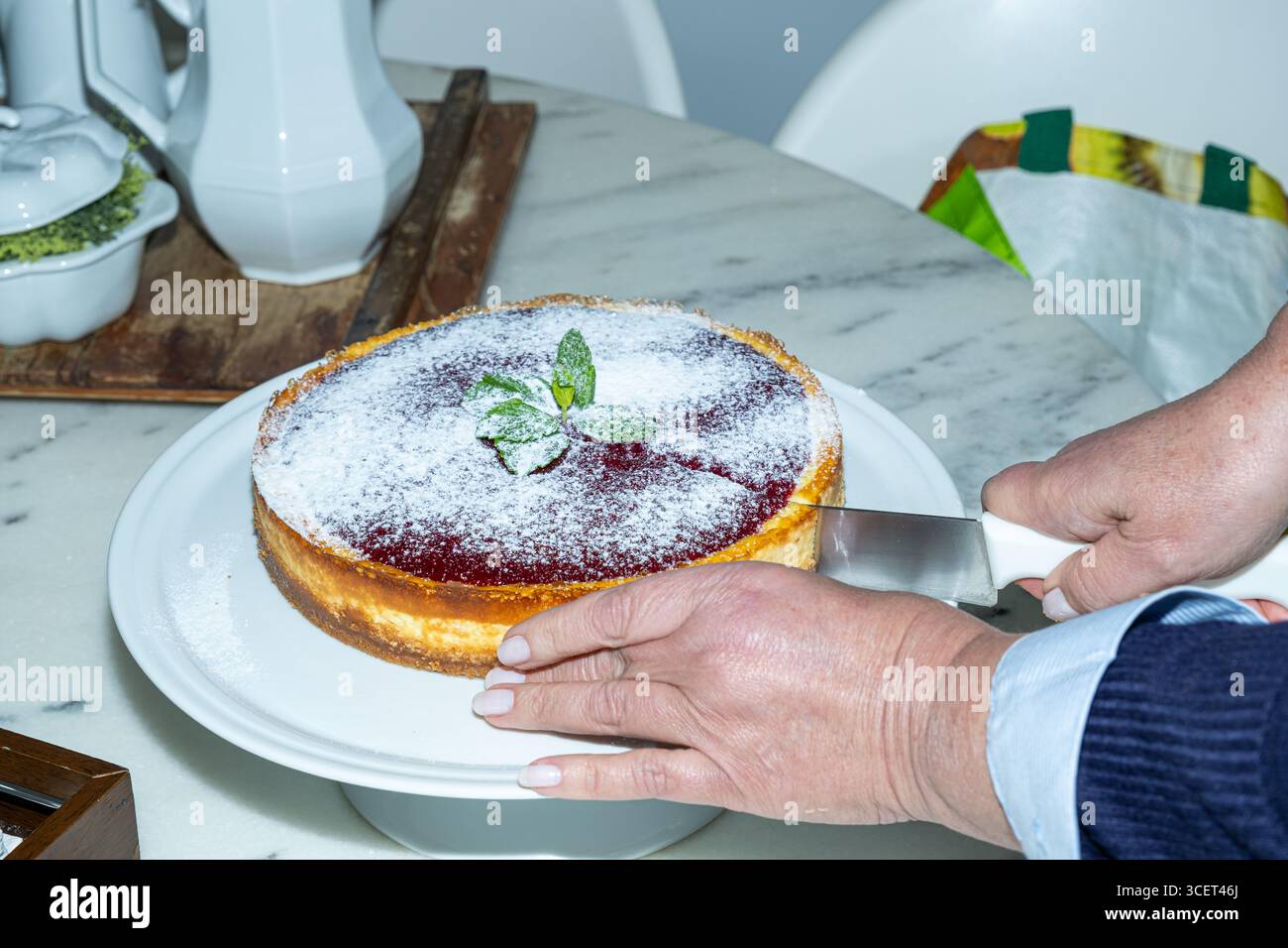 Donna che taglia una fetta di cheesecake con una marmellata di frutti di bosco. Foto Stock