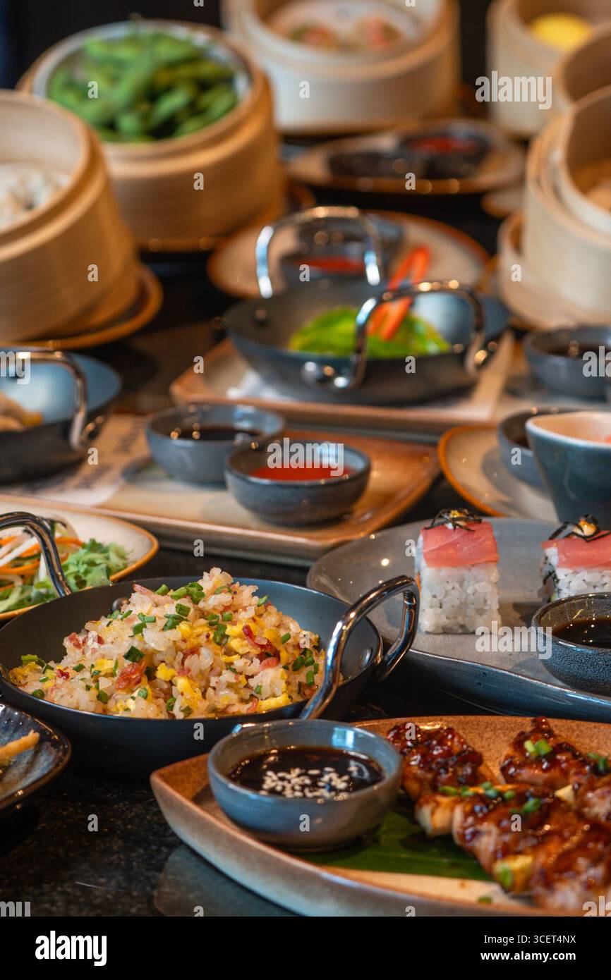 Assortimento di piatti cinesi. Spaghetti cinesi, riso fritto, gnocchi, dim sum, involtini primavera. Famosi piatti della cucina cinese su sfondo nero Foto Stock