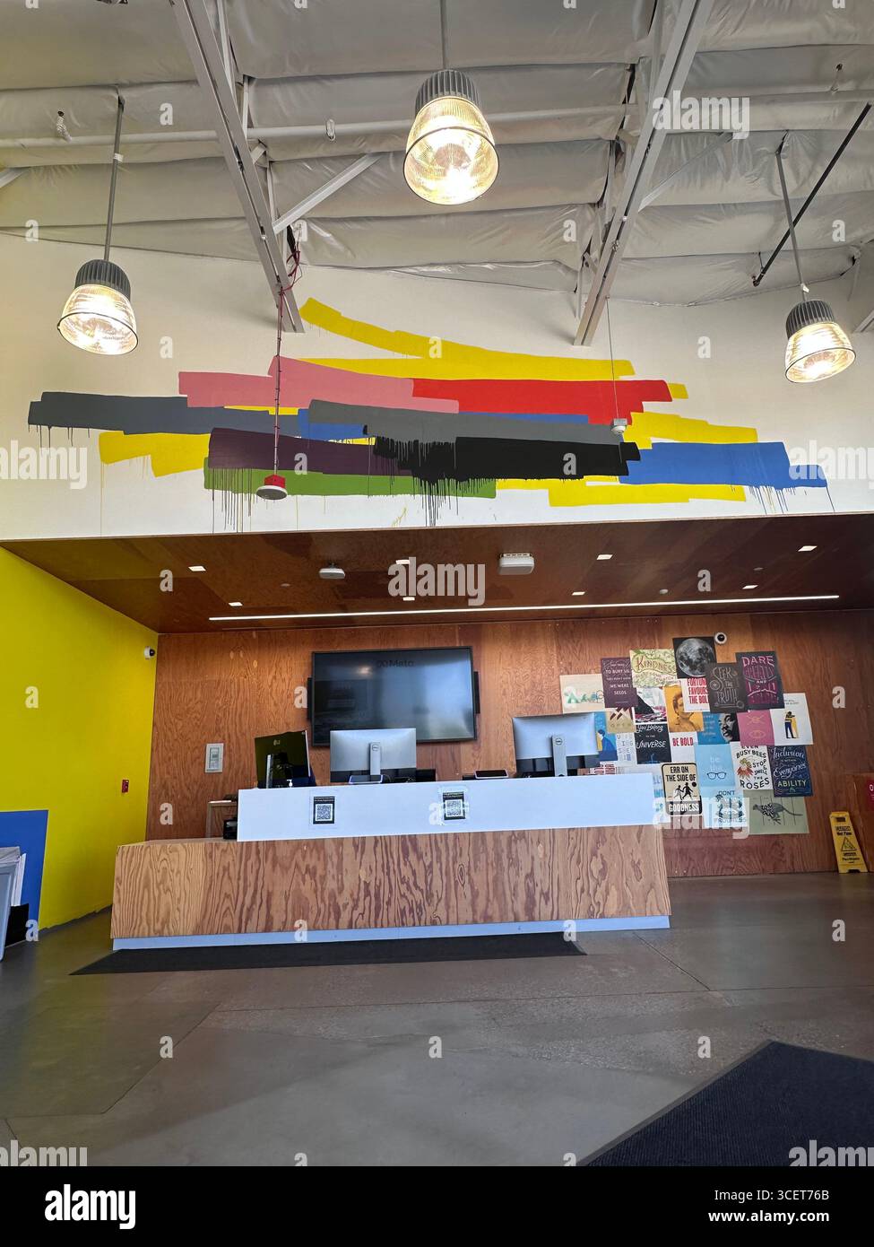 Una moderna area ricevimento caratterizzata da un audace murale astratto con vivaci strisce di vernice in giallo, rosso, blu, rosa, grigio, verde e nero. Foto Stock