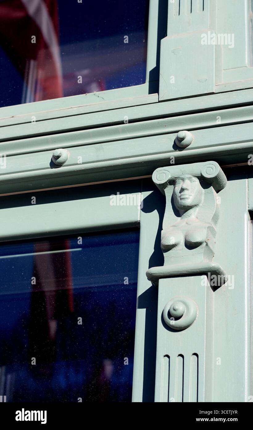 Il forte e grazioso busto di una donna come a parte di una cornice di finestra su un edificio a riga, in Lettonia. Un dettaglio scultoreo noto come herma. Foto Stock