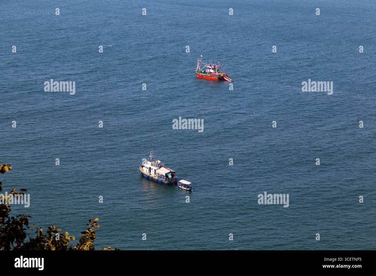 Un sereno colpo dal forte di Ratnadurga che mostra il lungo molo che si estende nel turchese Mar Arabico, circondato da acque calme e colline verdi lontane Foto Stock