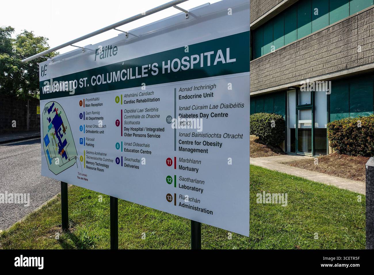 Cartello d'ingresso al St. Columcille's Hospital, Loughlinstown, Dublino, Irlanda, che mostra i reparti medici e i servizi sanitari sia in irlandese che in Engl Foto Stock