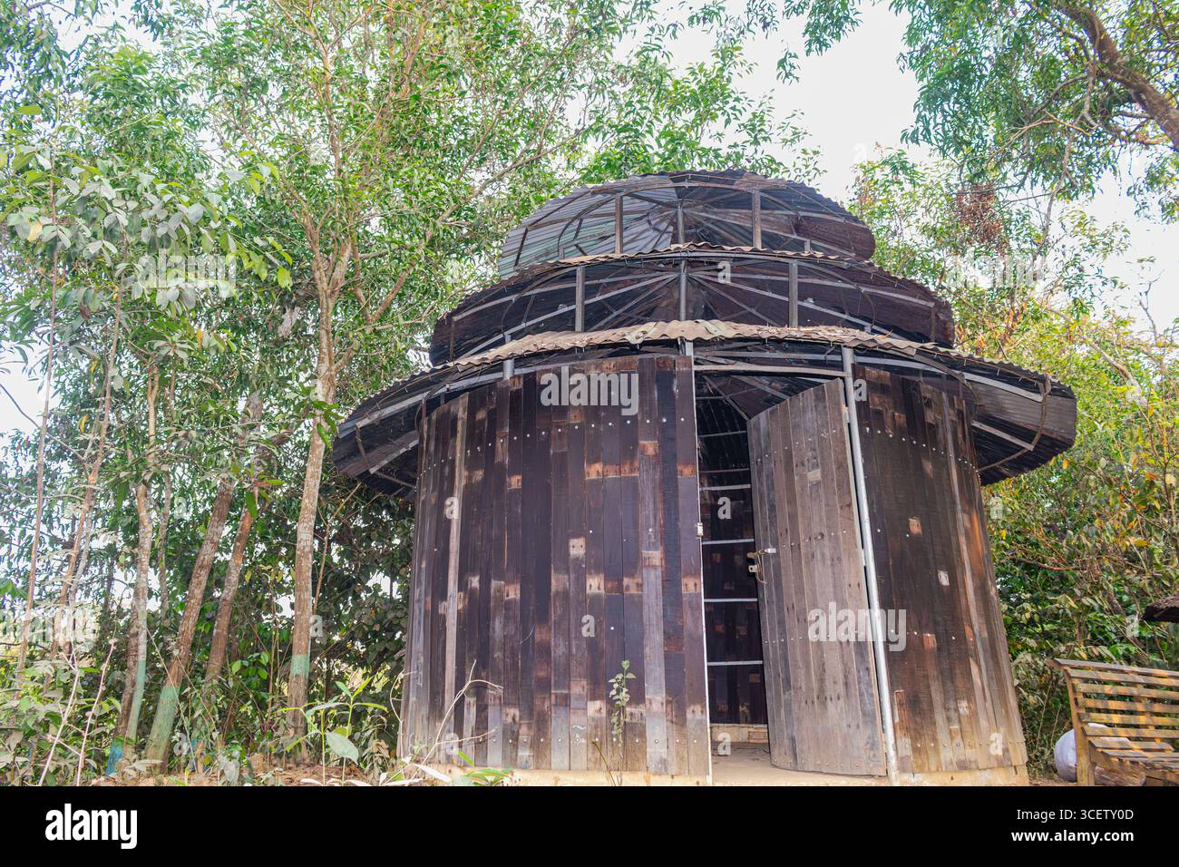 Antica capanna circolare del monastero costruita con legno in un ambiente naturale lussureggiante Foto Stock