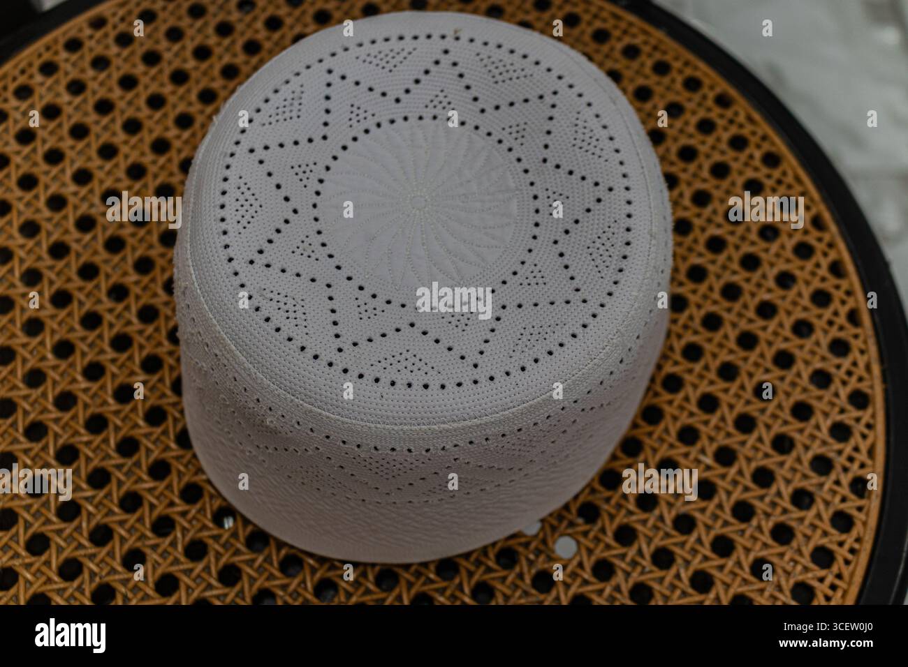 Berretto di preghiera islamico circolare con motivi geometrici dettagliati che poggiano sulla tessitura di canne marroni Foto Stock