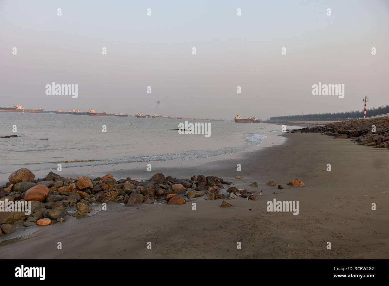 Rocce costiere che incorniciano una tranquilla vista sull'oceano con petroliere lontane in Bangladesh Foto Stock