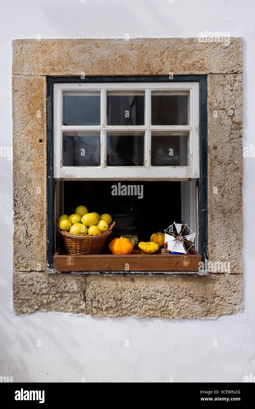Cesto intrecciato con limoni freschi, buongustai e un mulino a vento giocattolo su davanzale, Óbidos, Portogallo Foto Stock