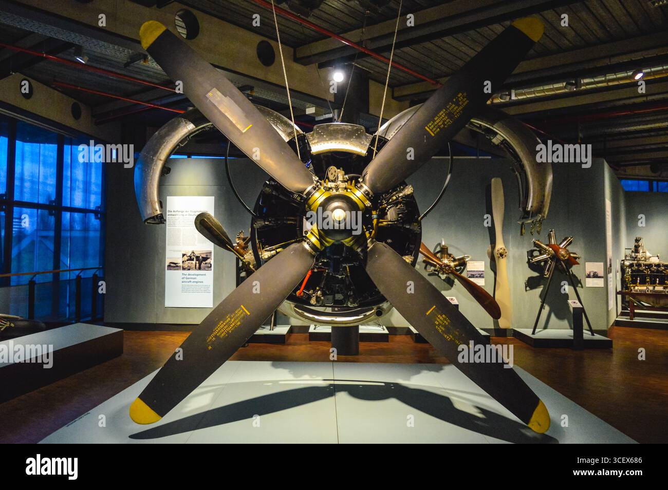 Grande motore aeronautico con elica a quattro pale in mostra al Museo tedesco della tecnologia di Berlino, circondato da mostre sull'aviazione. Foto Stock