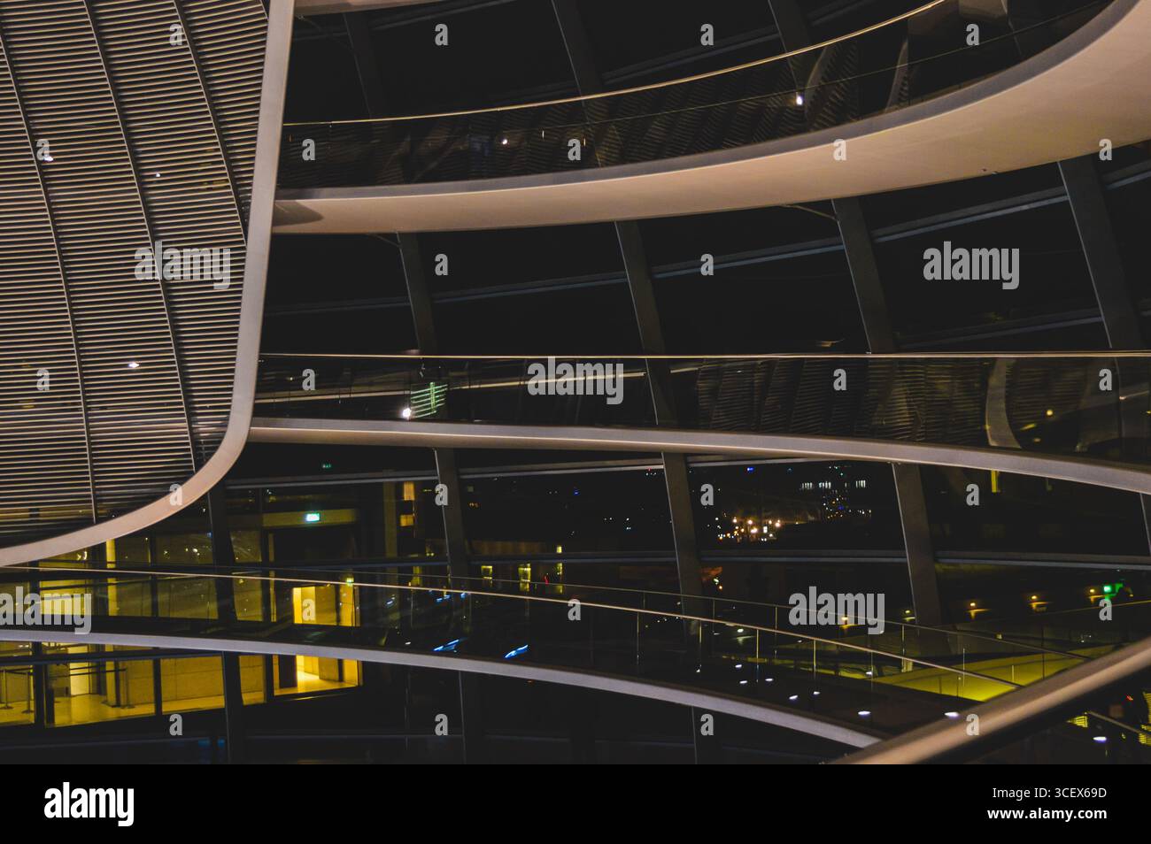 Passaggi interni curvi all'interno della cupola in vetro del Reichstag a Berlino, Germania, con architettura moderna illuminata e riflessi di notte. Foto Stock