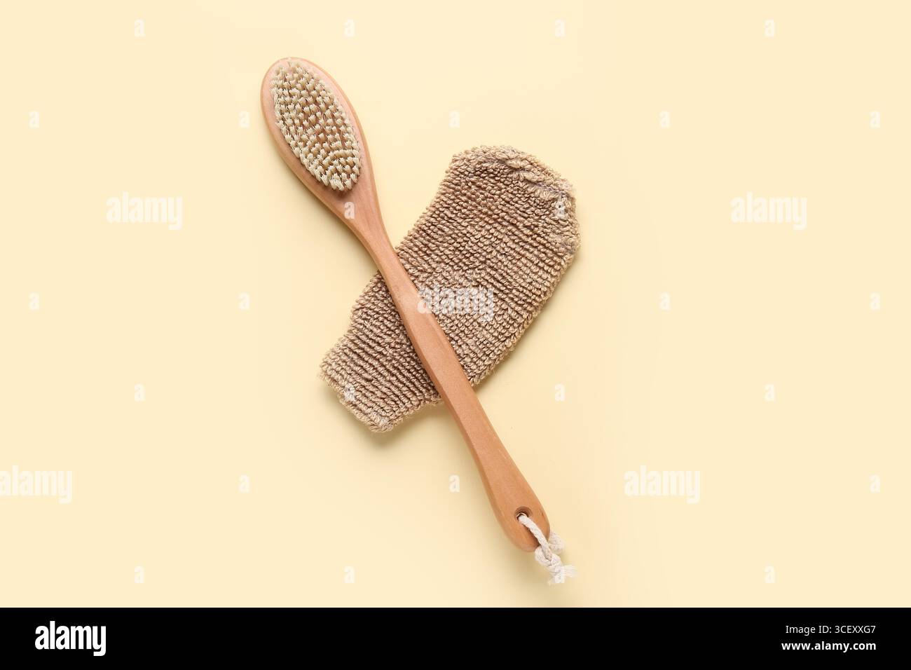 Composizione con guanto massaggiante e spazzola per il corpo massaggiante su sfondo beige Foto Stock