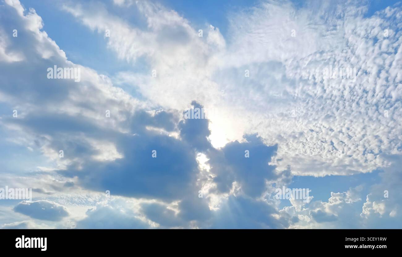 Le spettacolari formazioni nuvolose creano un'incredibile visualizzazione visiva quando la luce del sole si diffonde, illuminando il cielo blu e proiettando ombre morbide acro Foto Stock