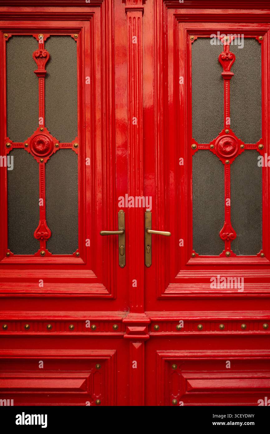 Doppia porta in legno rosso ornato con piano ad arco e pannelli decorativi in vetro Foto Stock