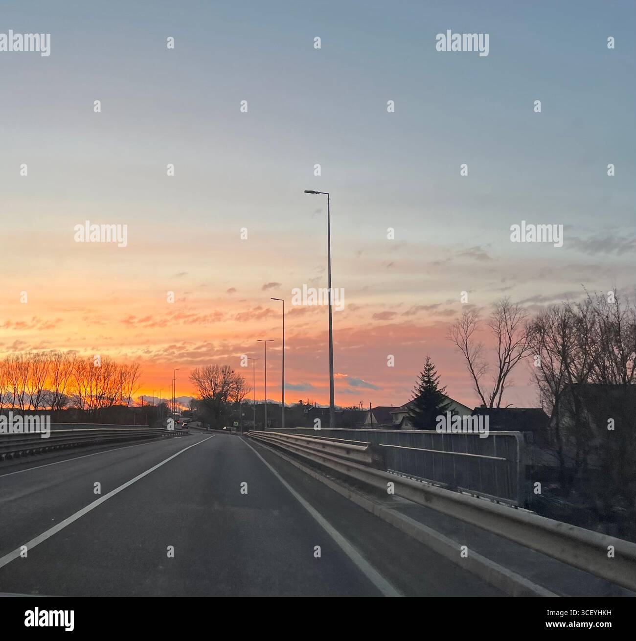 un dolce tramonto dorato davanti alla strada, ai campi e un viaggio sulla strada Foto Stock