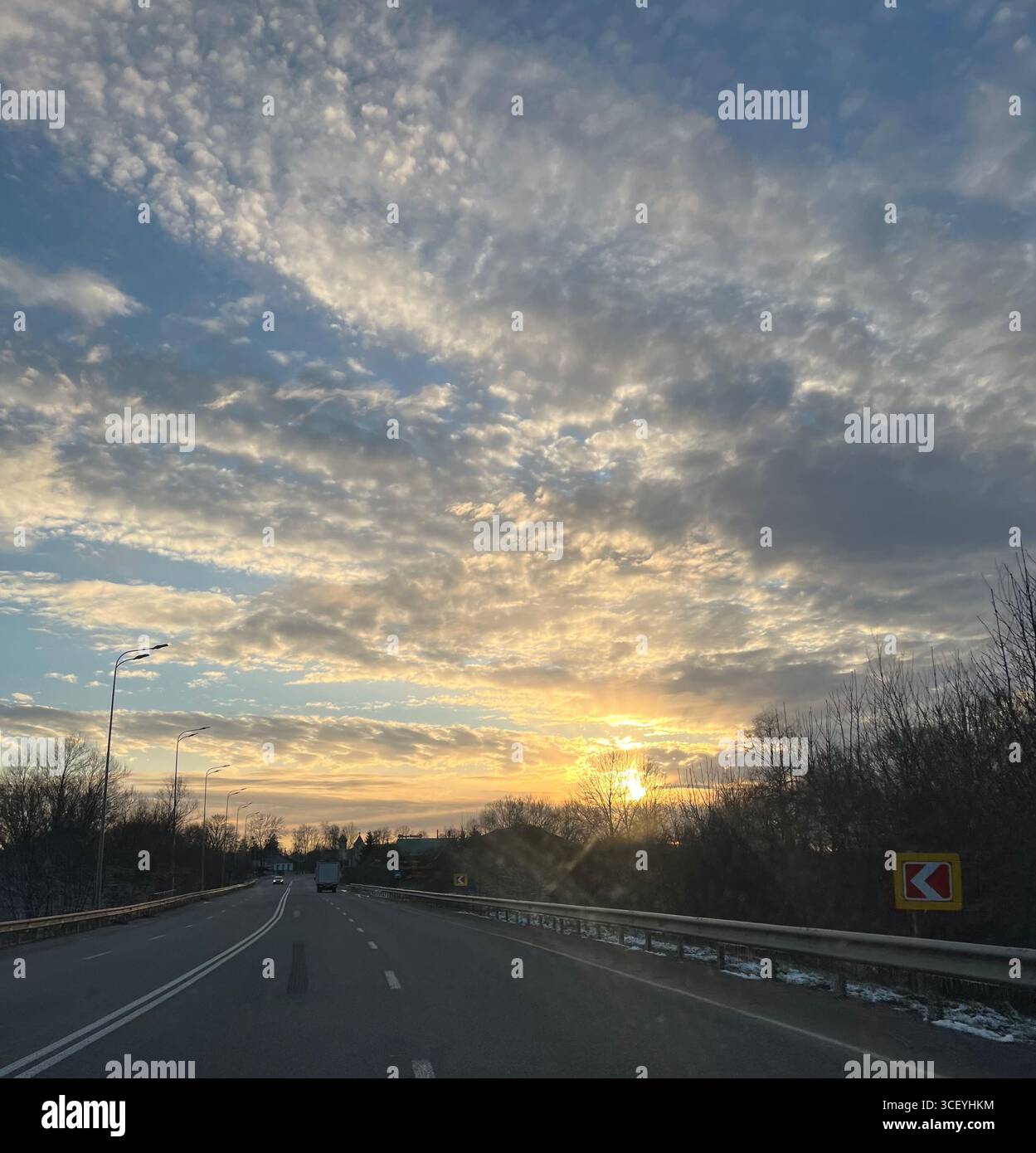 un dolce tramonto dorato davanti alla strada, ai campi e un viaggio sulla strada Foto Stock