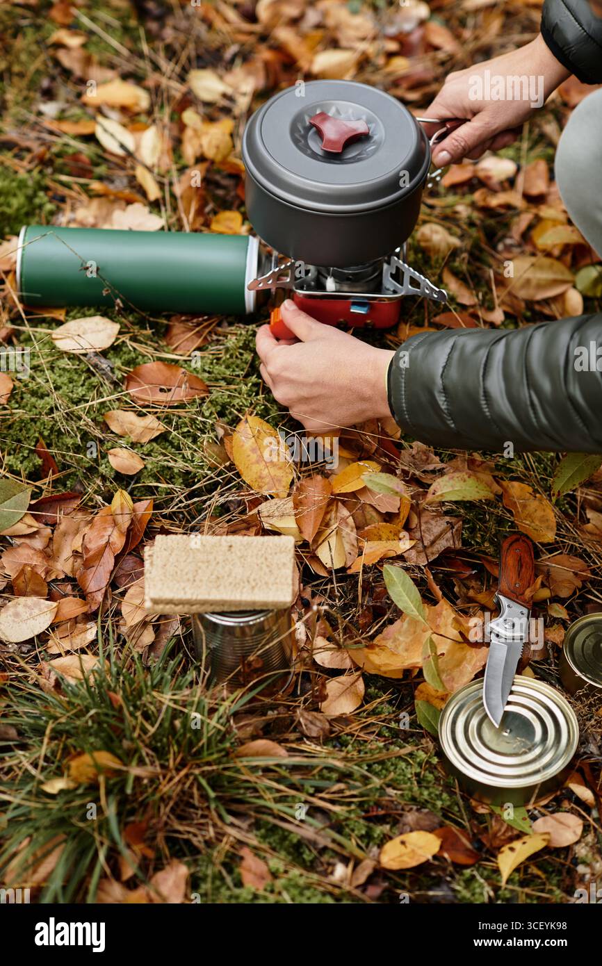 Una donna anziana gode di un momento di pace nella foresta, preparando un pasto caldo all'aperto. Foto Stock