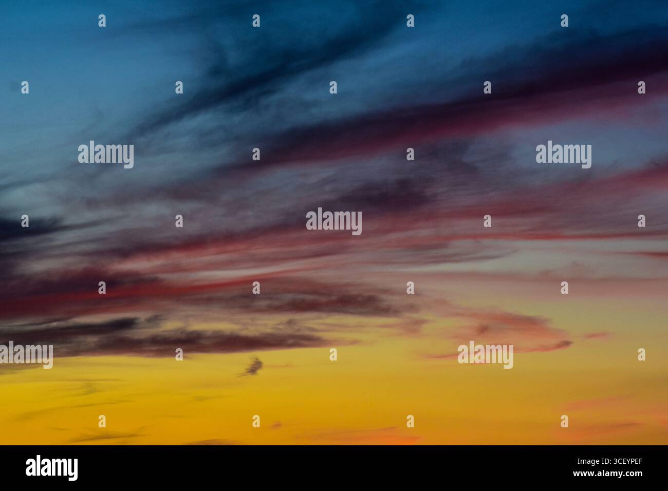 Le sfumature dorate e rosa danzano tra le nuvole morbide in un cielo tranquillo, catturando la calma bellezza del crepuscolo. Foto Stock