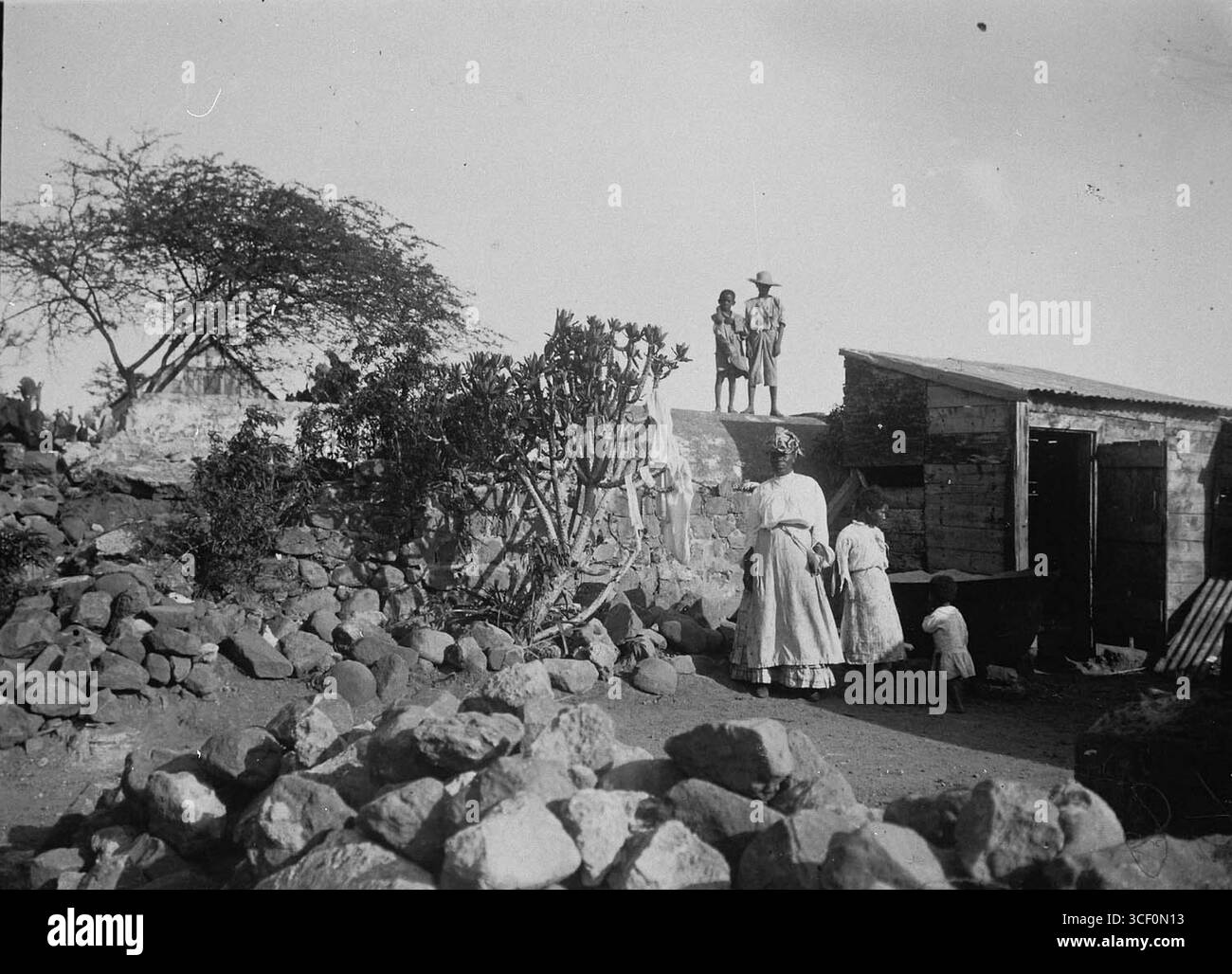 Fotografia dei residenti che posano nel loro cortile vicino alla casa, scattata tra il 1900 e il 1940. Il fotografo è sconosciuto. Dimensioni: 8,6 x 11,8 cm. Foto Stock