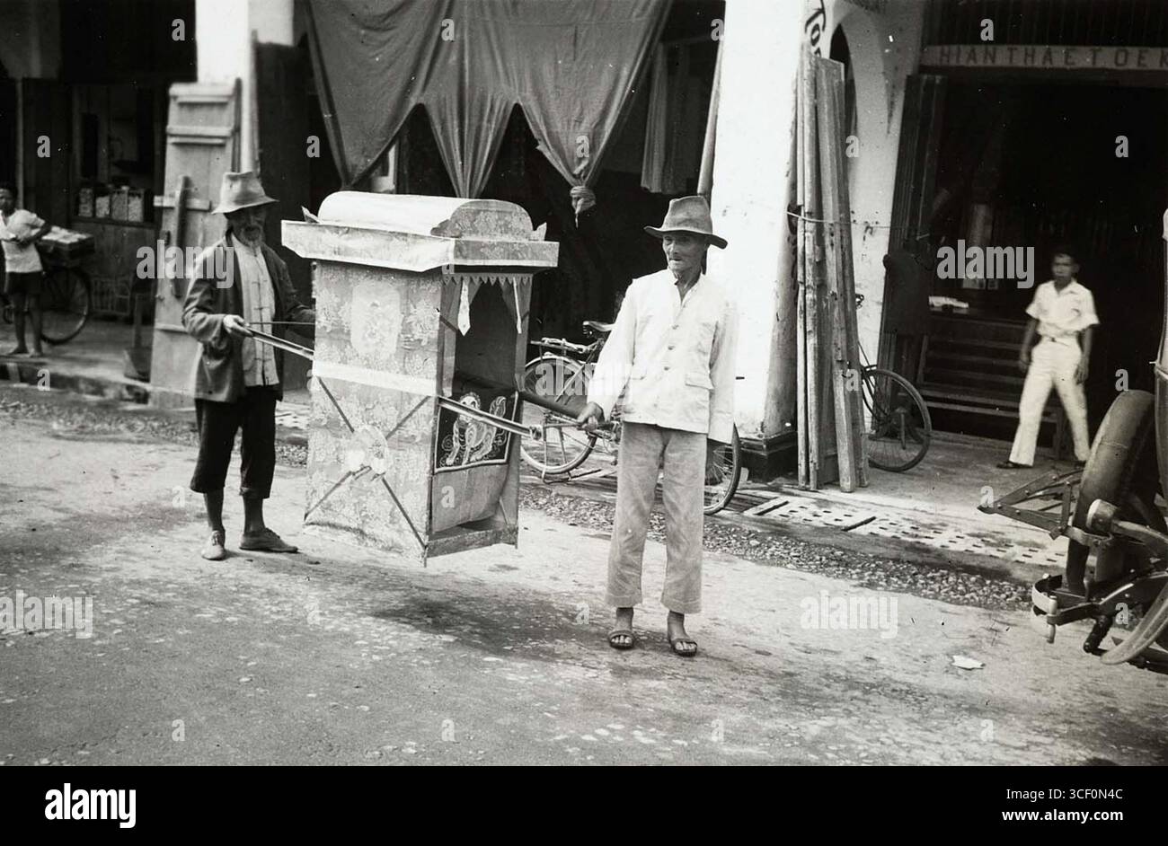 Questa fotografia, scattata tra il 1930 e il 1942, mostra due uomini cinesi che trasportano una sedia di carta berlina ad un funerale, dove verrà bruciata in onore del defunto secondo le usanze funerarie cinesi. Foto Stock