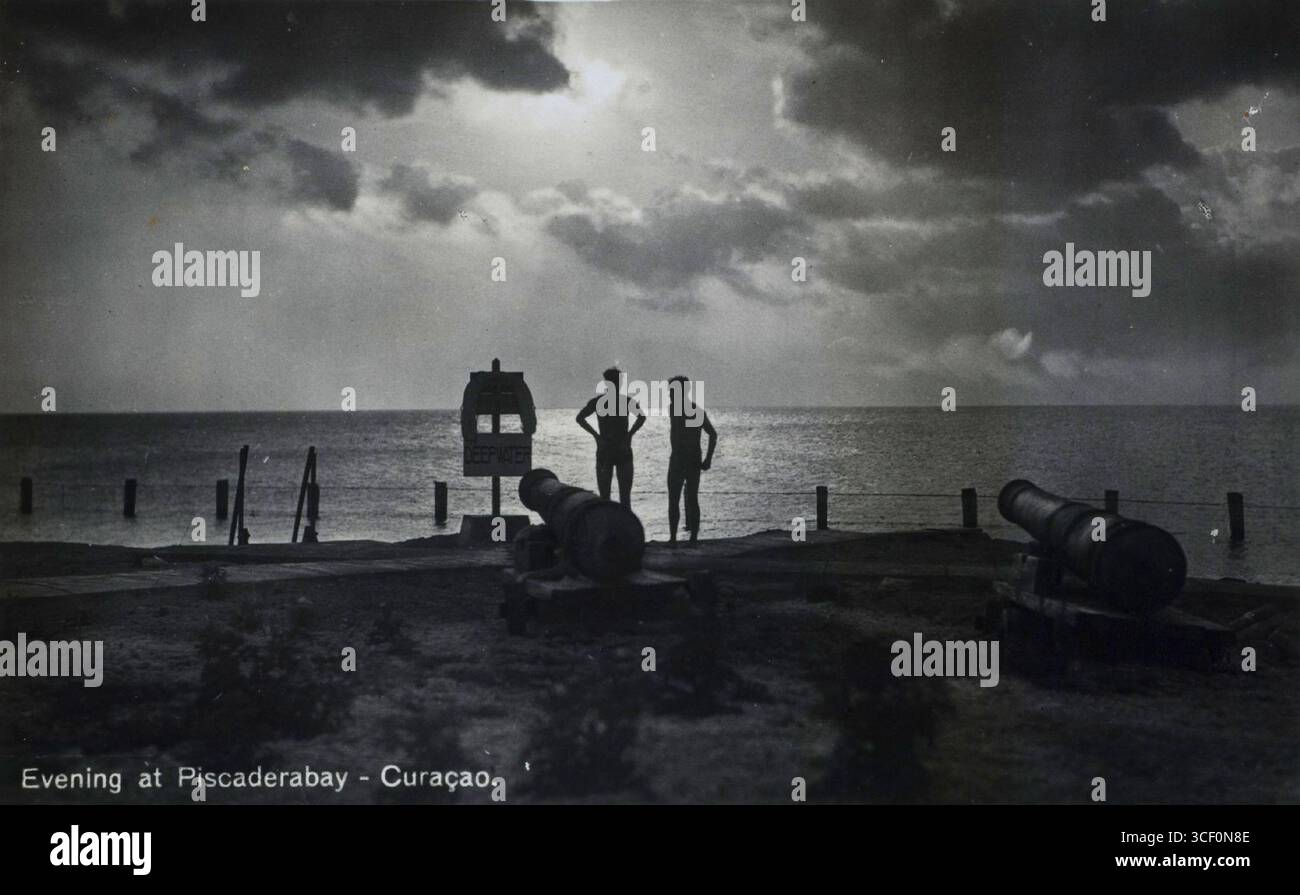 Una scena serale a Piscaderabay, Curacao, scattata da un fotografo sconosciuto tra il 1929 e il 1940. La foto misura 9 x 14 cm e mostra la baia nelle ore del crepuscolo, offrendo uno scorcio storico della posizione all'inizio del XX secolo. Foto Stock