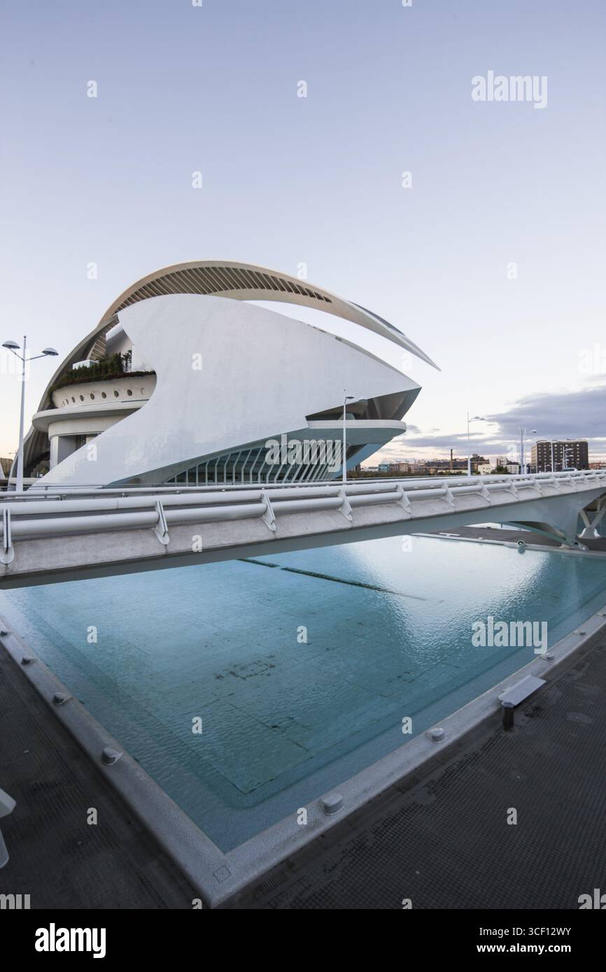 Edificio moderno dal design curvo accanto ad una piscina riflettente al tramonto dell'Opera Foto Stock