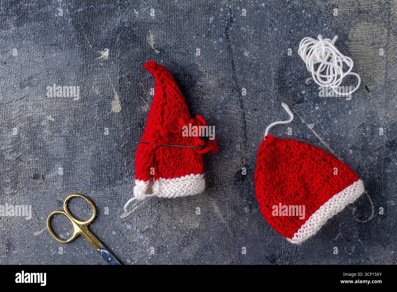 Lavorazione a maglia dei cappelli di Babbo Natale su sfondo blu, passaggio 4 Foto Stock