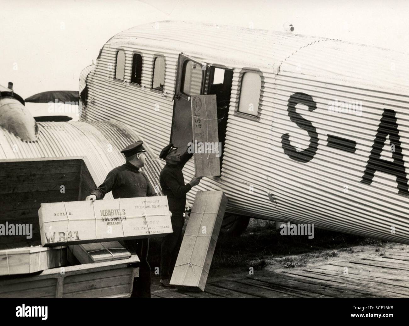 Questa foto del 1927 mostra i pacchi postali caricati su un aereo da posta aerea all'aeroporto di Schiphol, illustrando i primi servizi di posta aerea e la logistica aerea. Foto Stock