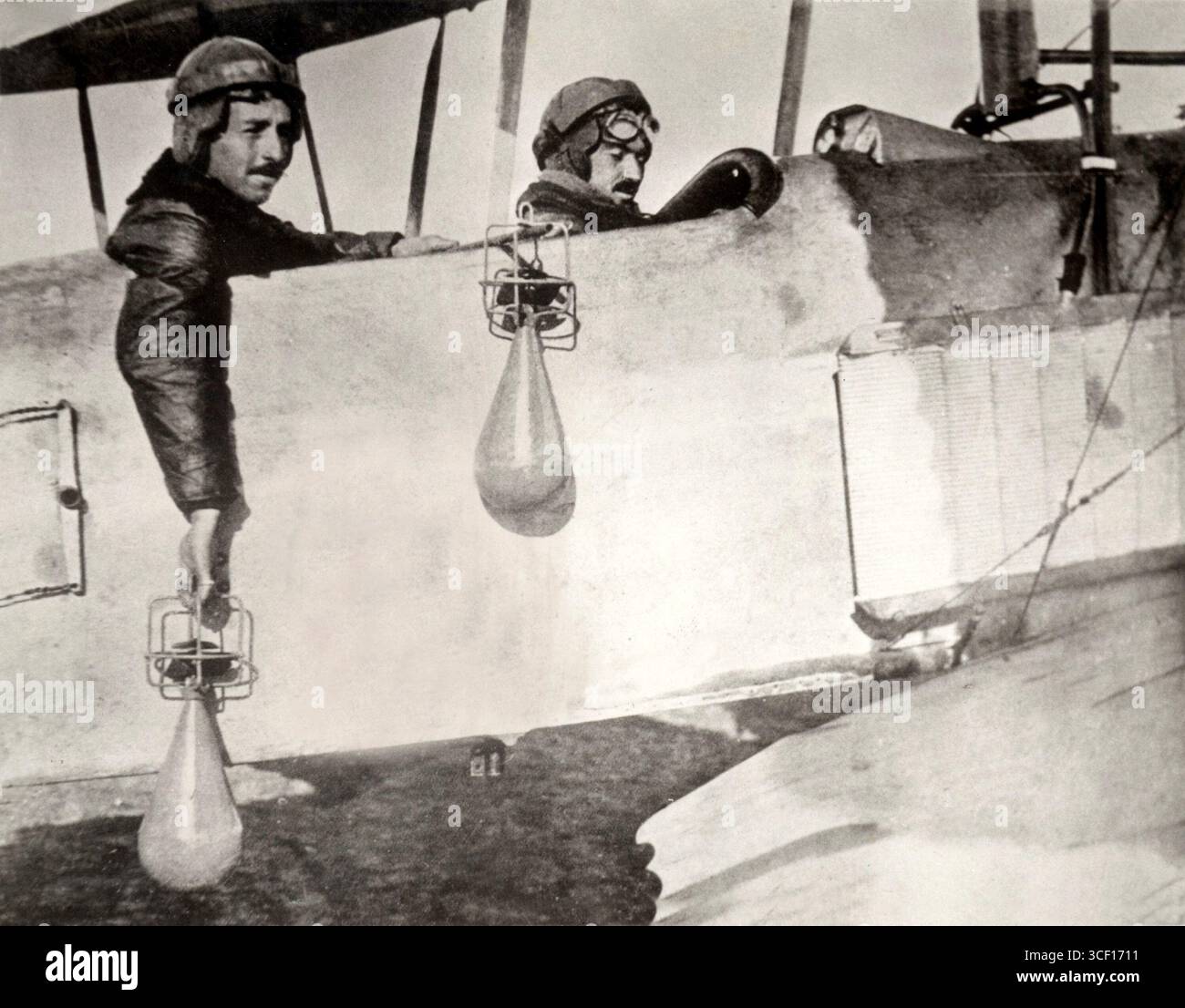 Questa immagine del 1914 mostra i piloti che lanciano bombe a mano dagli aerei durante la prima guerra mondiale. La foto cattura una prima tattica utilizzata nella guerra aerea. Foto Stock