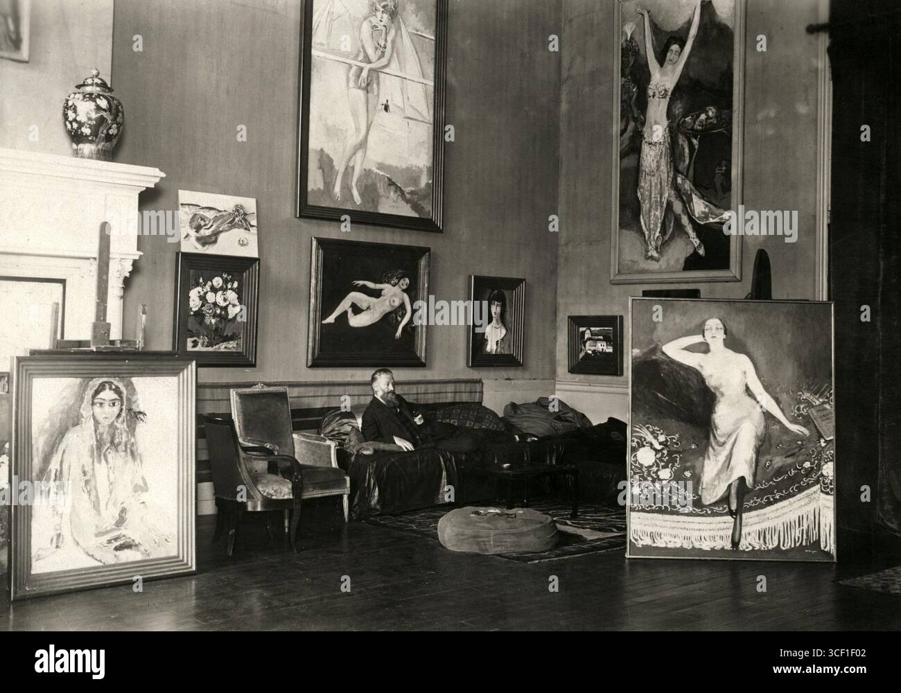 Nel 1929, Kees van Dongen (1877-1968), l'artista olandese-francese, è seduto su un divan circondato dai suoi dipinti in una stanza della sua villa a Parigi. Foto Stock