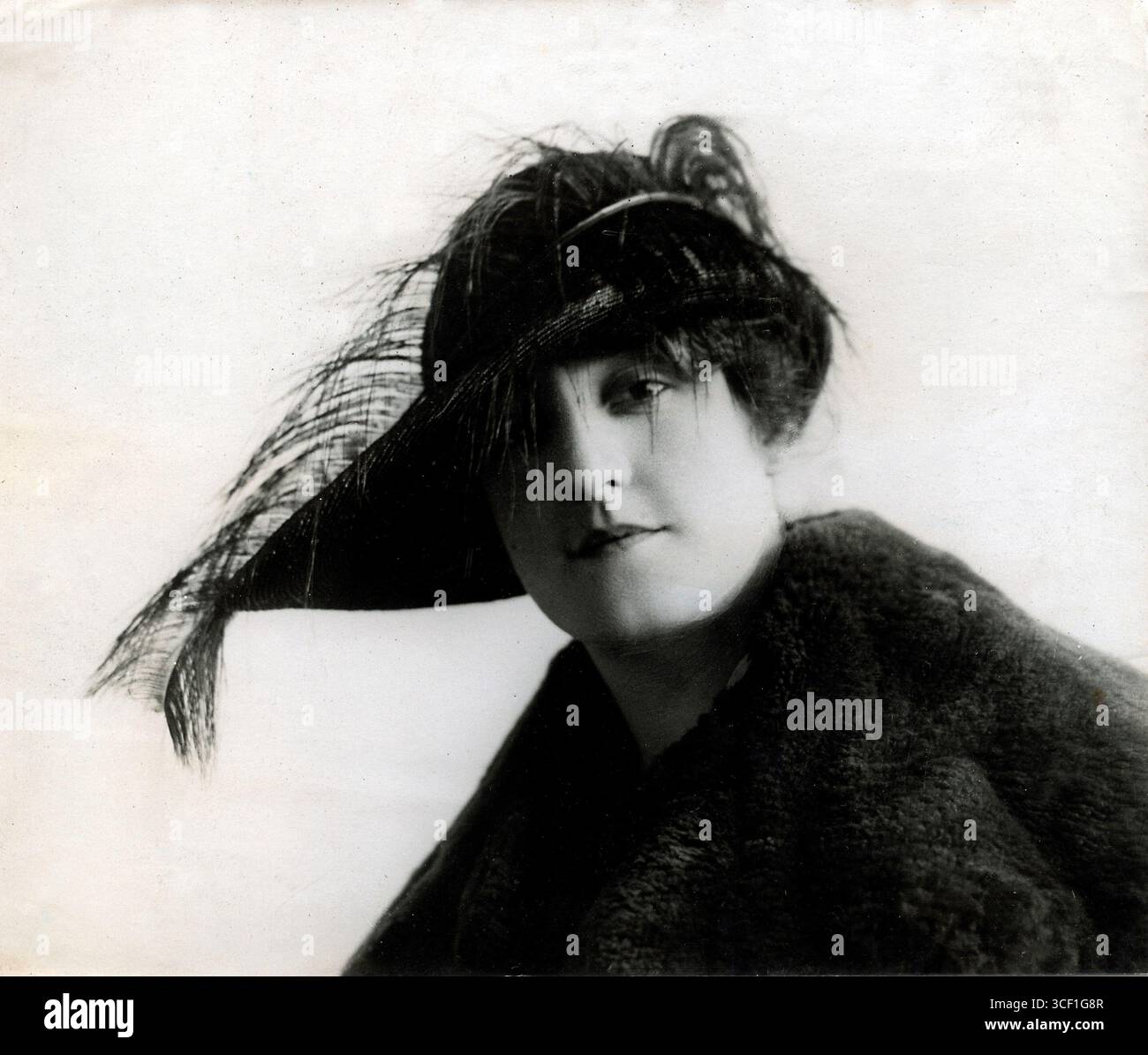 Moda parigina da donna del 1919, caratterizzata da un cappello asimmetrico impreziosito da piume e colletto in pelliccia, sfoggia un design audace e all'avanguardia. Foto Stock