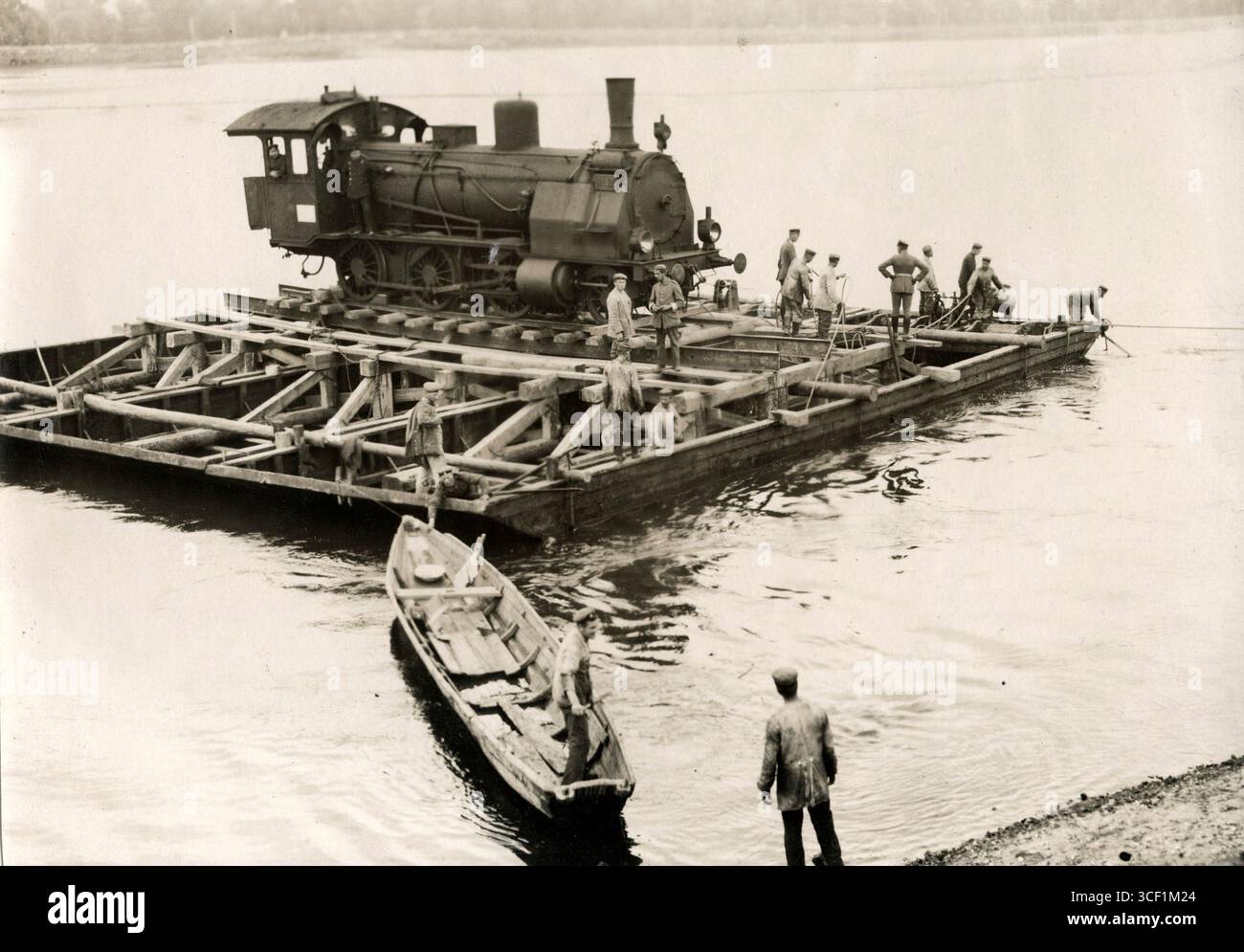 Prima guerra mondiale sul fronte orientale. Una locomotiva tedesca viene trasportata attraverso un fiume su una grande zattera. 1915. Foto Stock