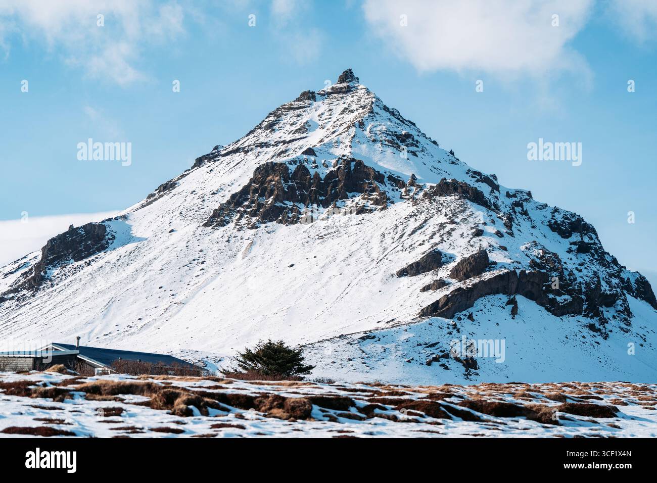 Picco innevato a forma di piramide sopra una pianura costiera, penisola di Snæfellsnes, Islanda occidentale, Islanda Foto Stock