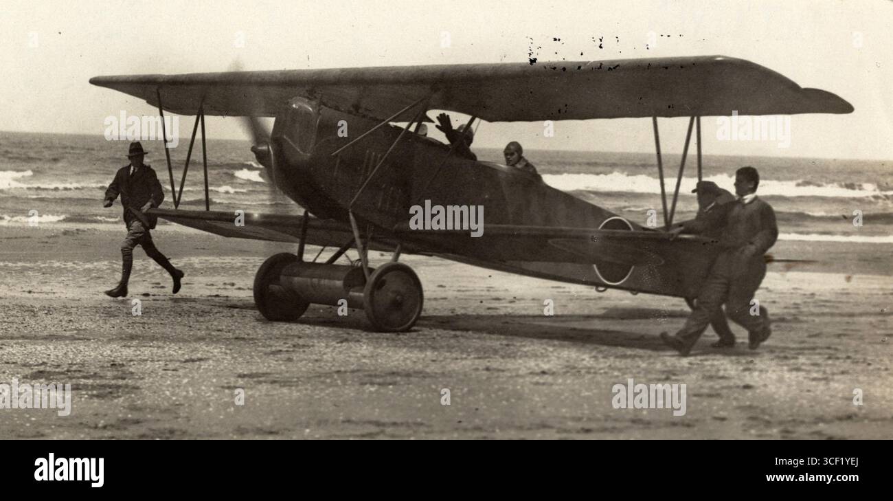 Un piccolo aereo, destinato alla rotta Scheveningen-Zandvoort, viene spinto lungo la spiaggia da un gruppo di uomini. L'immagine cattura un momento nella storia dell'aviazione, ambientato sulla spiaggia del Mare del Nord nei Paesi Bassi nel 1919. Foto Stock