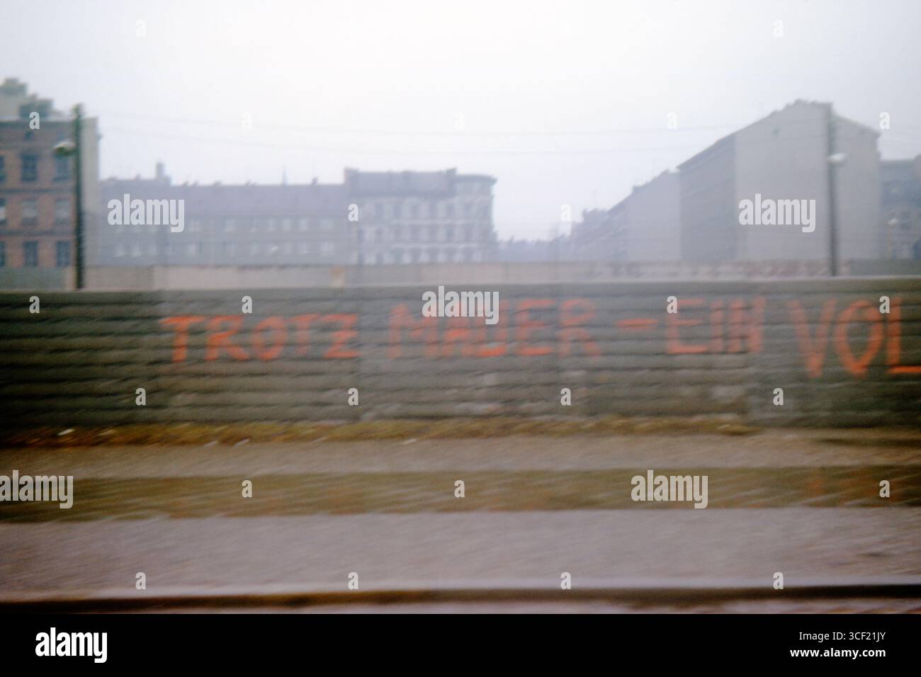 Graffiti che recitano "Trotz Mauer - Ein Volk" sul muro di Berlino vicino al Checkpoint Charlie, aprile 1963. Foto scattata da un'auto in movimento. Foto Stock