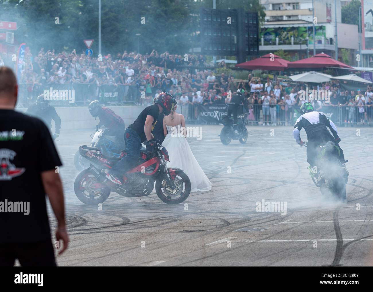 I piloti acrobatici bruciano le gomme intorno agli sposi alla festa della moto a Banja Luka, sposa e sposo in fumo Foto Stock