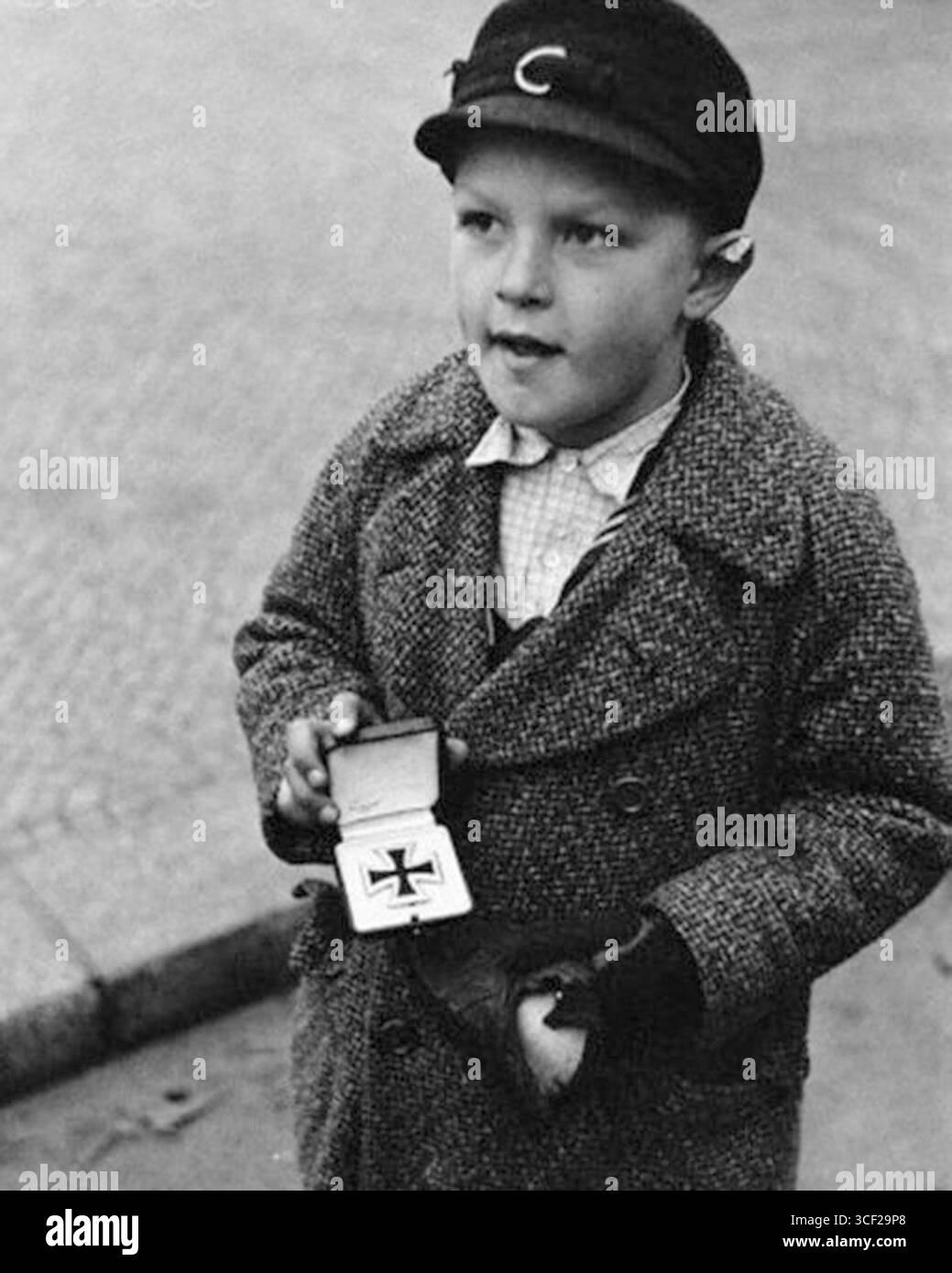 Un ragazzo tedesco che tentava di vendere la medaglia di Croce di ferro di suo padre, morto nella seconda guerra mondiale, in cambio di sigarette nel dicembre 1945. Questa immagine riflette le difficoltà incontrate dai civili dopo la guerra in Germania. Foto Stock