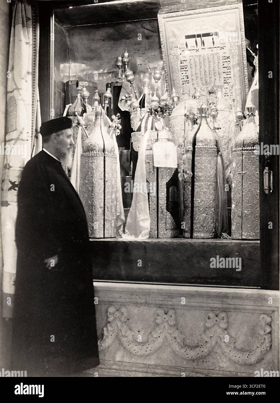 Questa fotografia del 1929 mostra un rabbino a Bayreuth, in Germania, accanto a un rotolo della Torah riccamente decorato, il testo sacro ebraico. La Torah è adornata con pietre preziose, sottolineando la sua importanza nella tradizione ebraica. Foto Stock