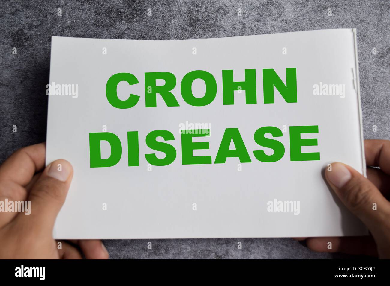 Concetto di malattia di Crohn scrivere su libro isolato su tavolo di legno. Foto Stock